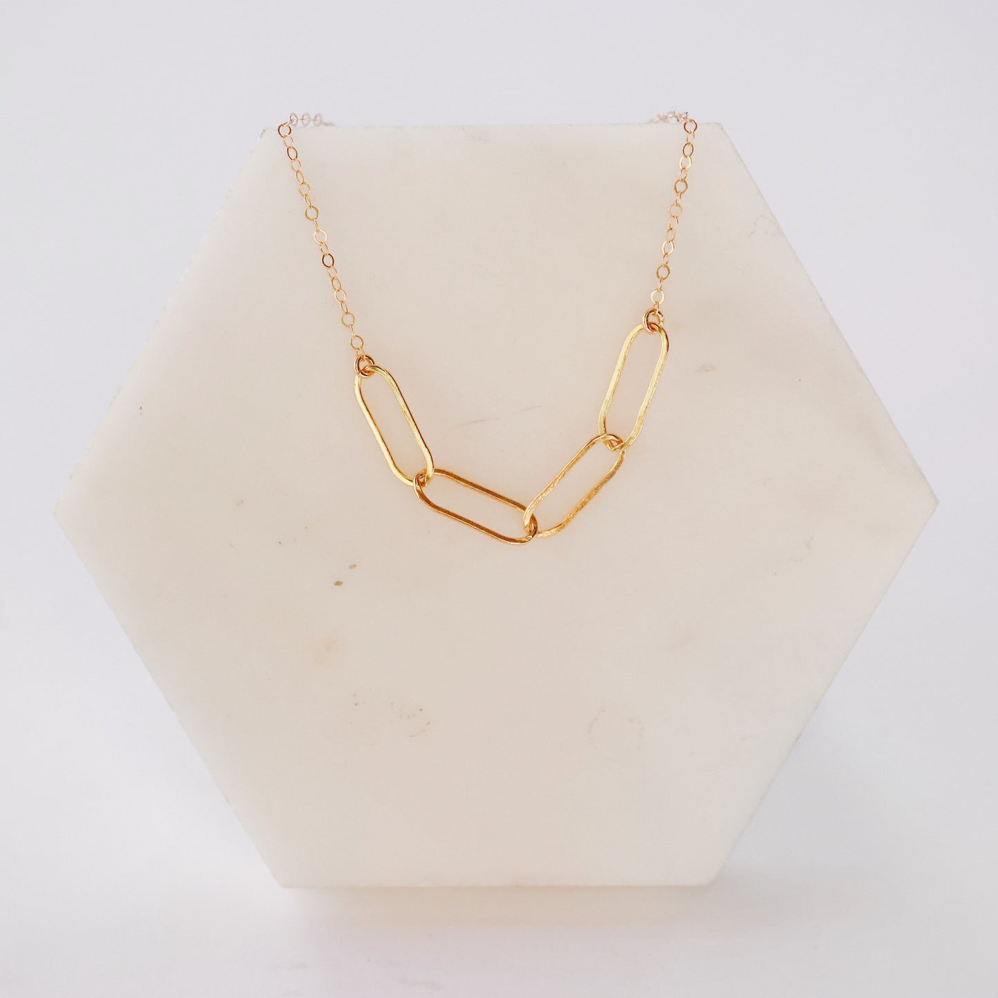 Gold necklace with a V-shaped pendant on a white background