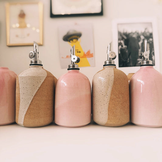 Set of ceramic bottles with pink and beige design on a white surface.