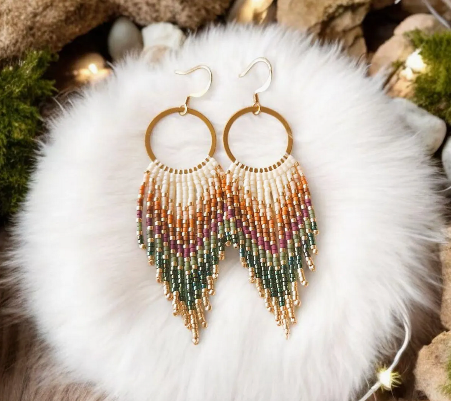 Multicolored beaded earrings on a white fur surface with a natural stone background