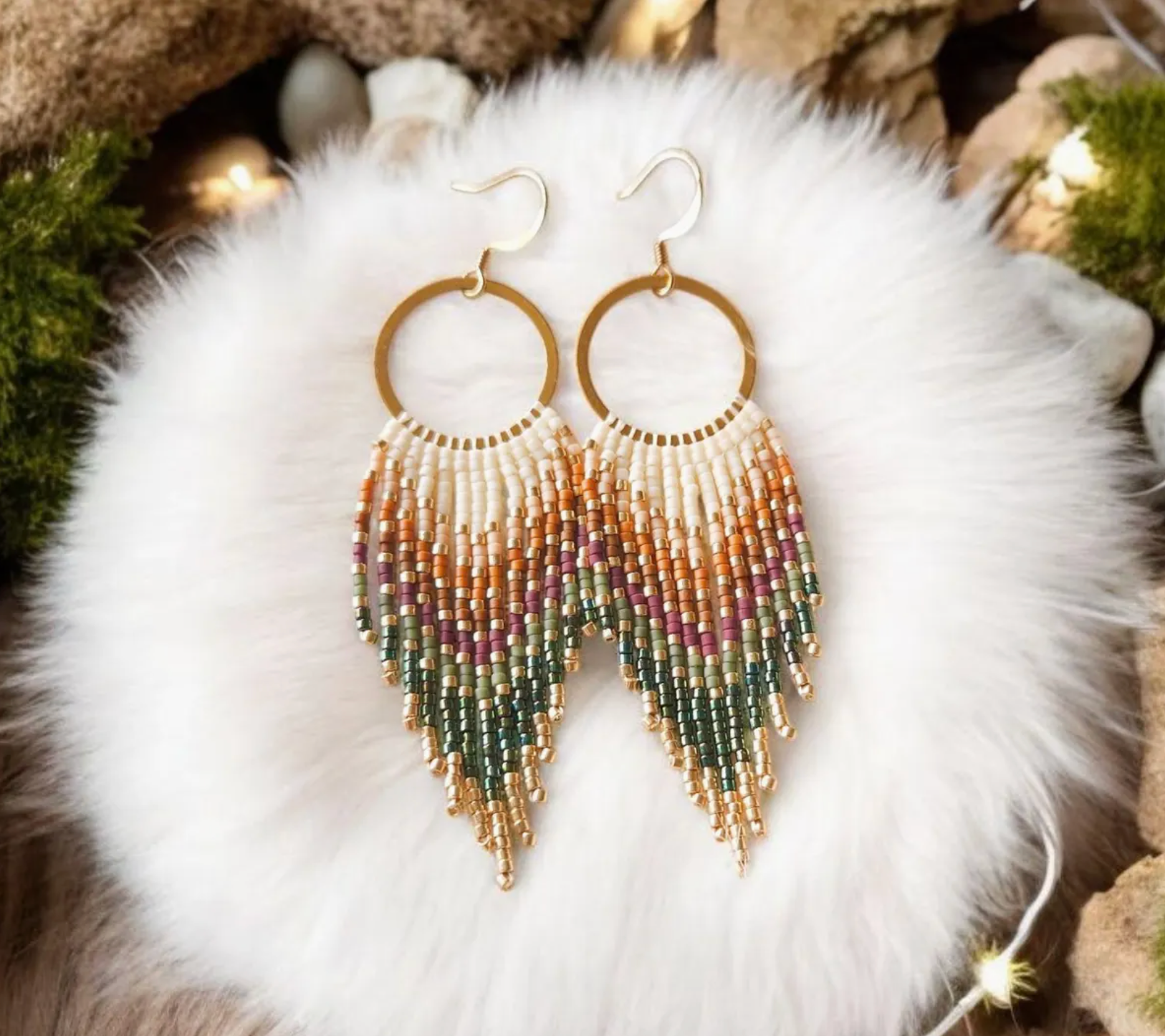 Multicolored beaded earrings on a white fur surface with a natural stone background