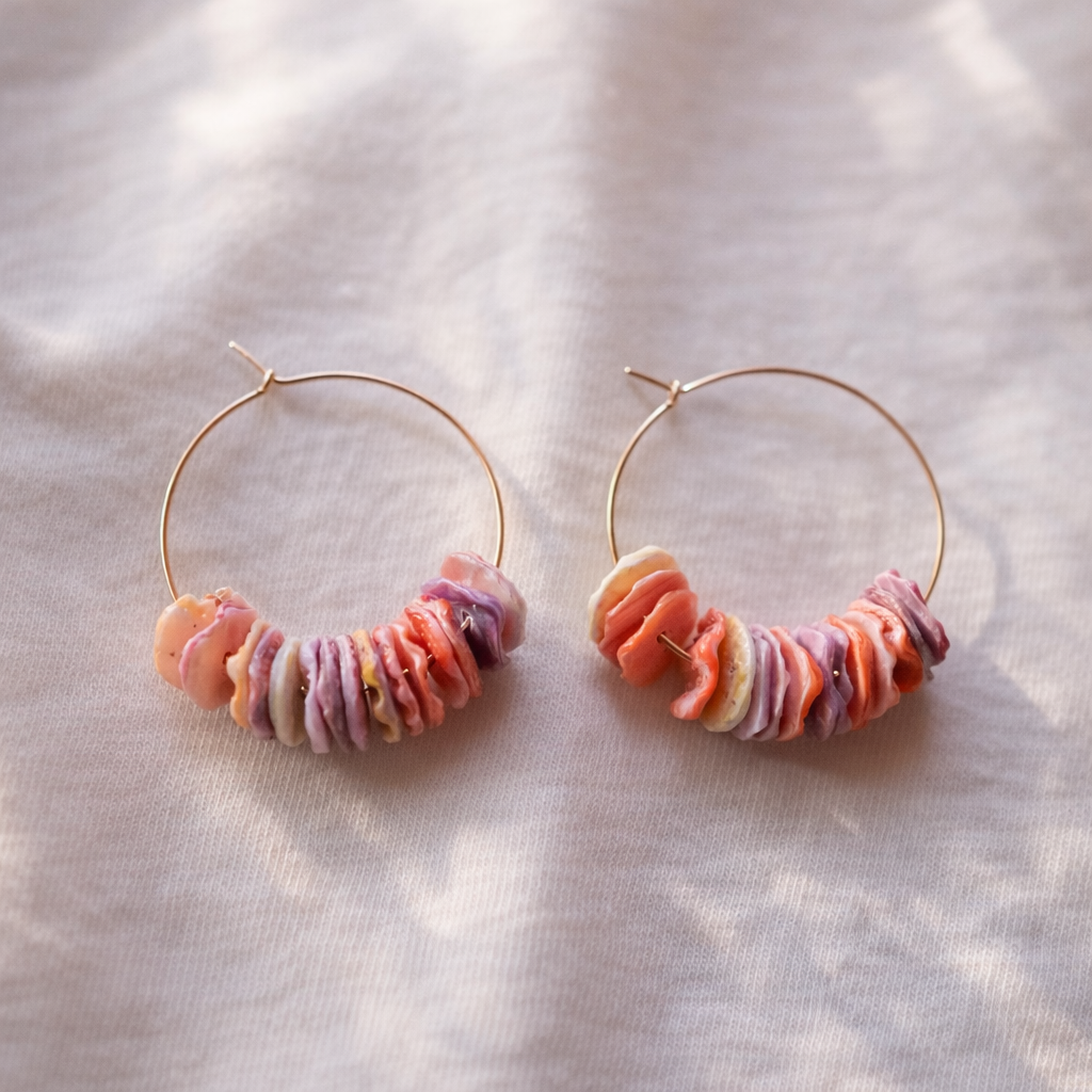 Hoop earrings with colorful bead accents on a light fabric background