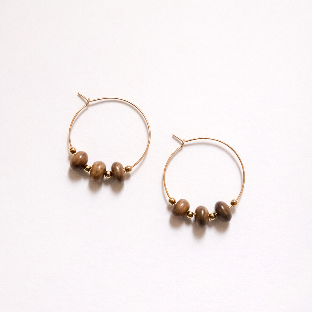 Pair of gold hoop earrings with brown beads on a white background