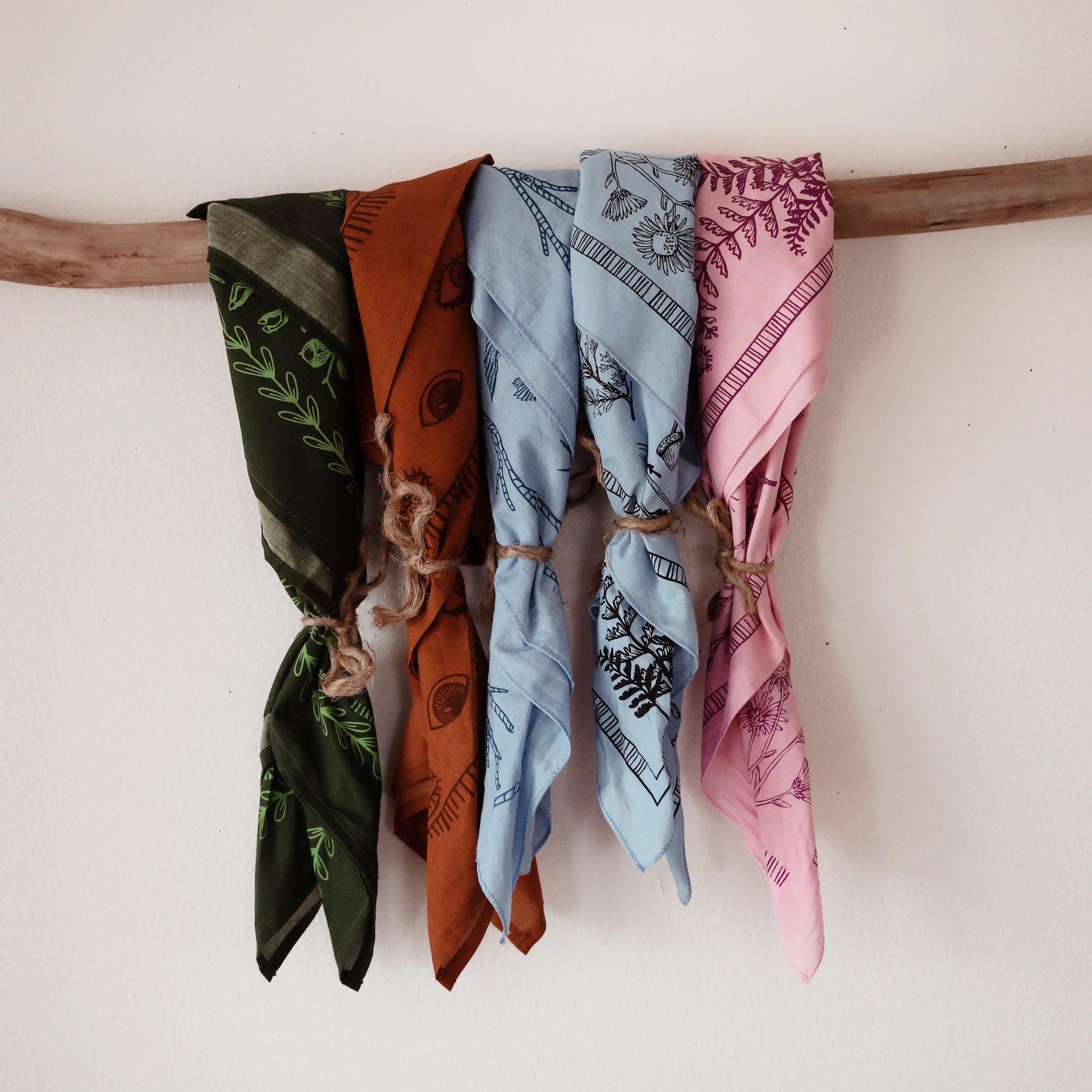 outdoorsy bandanas in baby blue, green, rust and pink hanging on a branch