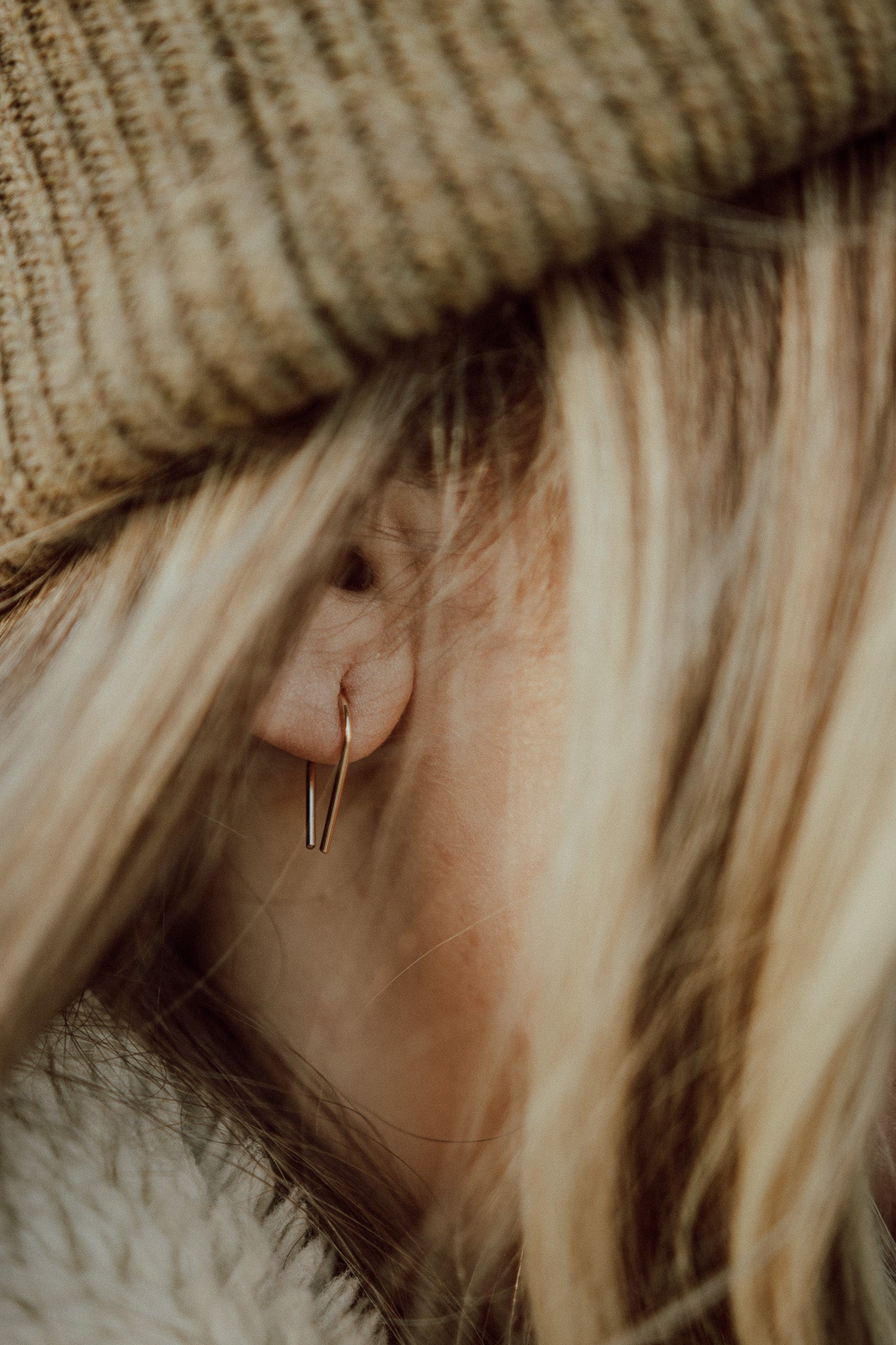 minimalist arch earring modeled on a woman with blonde hair wearing a beanie