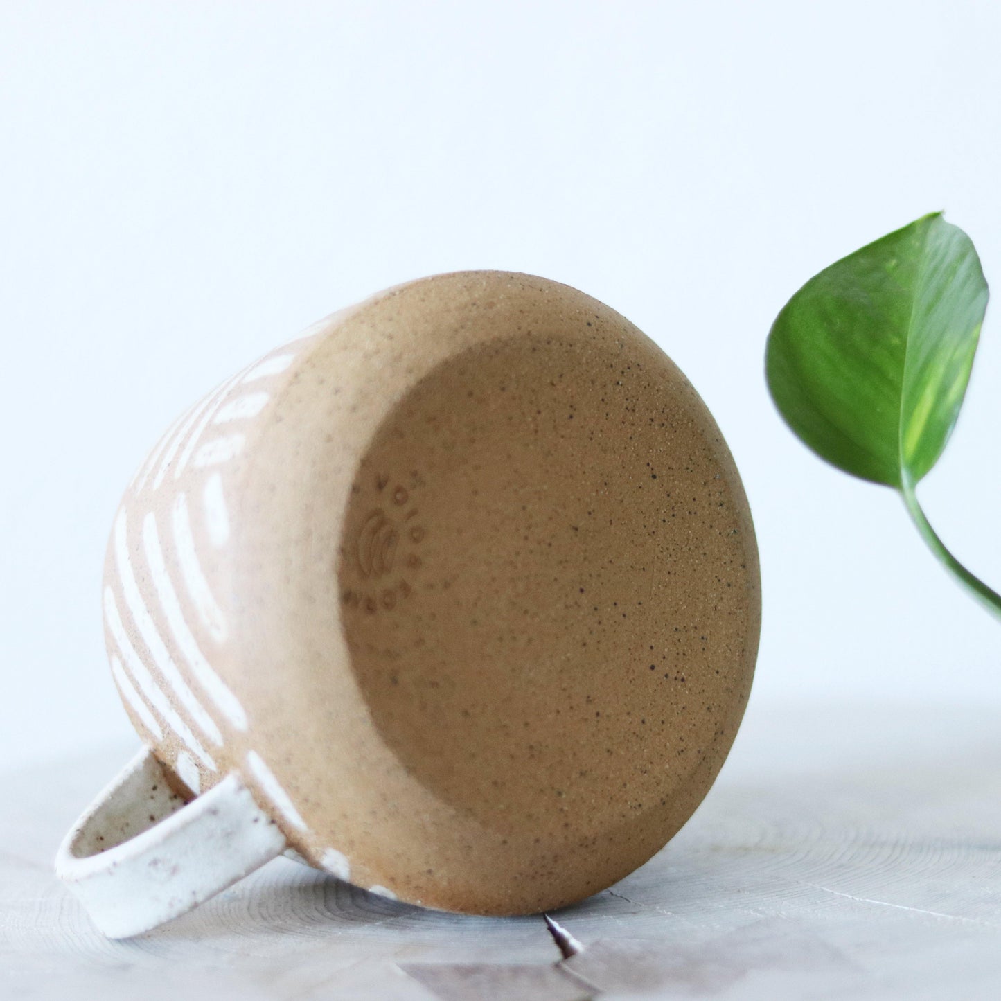 Handmade neutral mug with a speckled clay body and handpainted lines. Made by void and form ceramics.