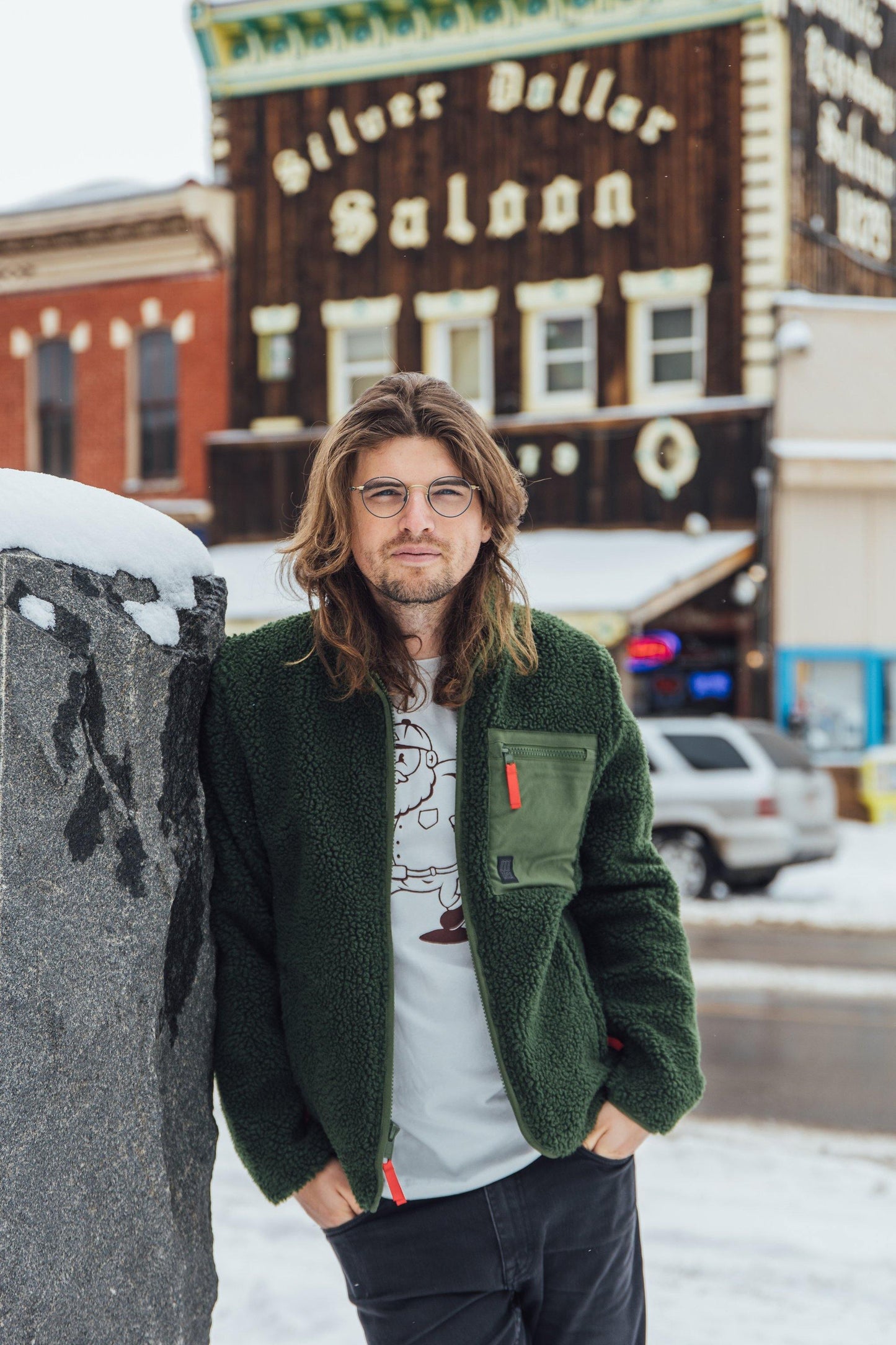 Man wearing olive green reversible sherpa jacket in front of the Silver Dollar Saloon in Leadville, Colorado