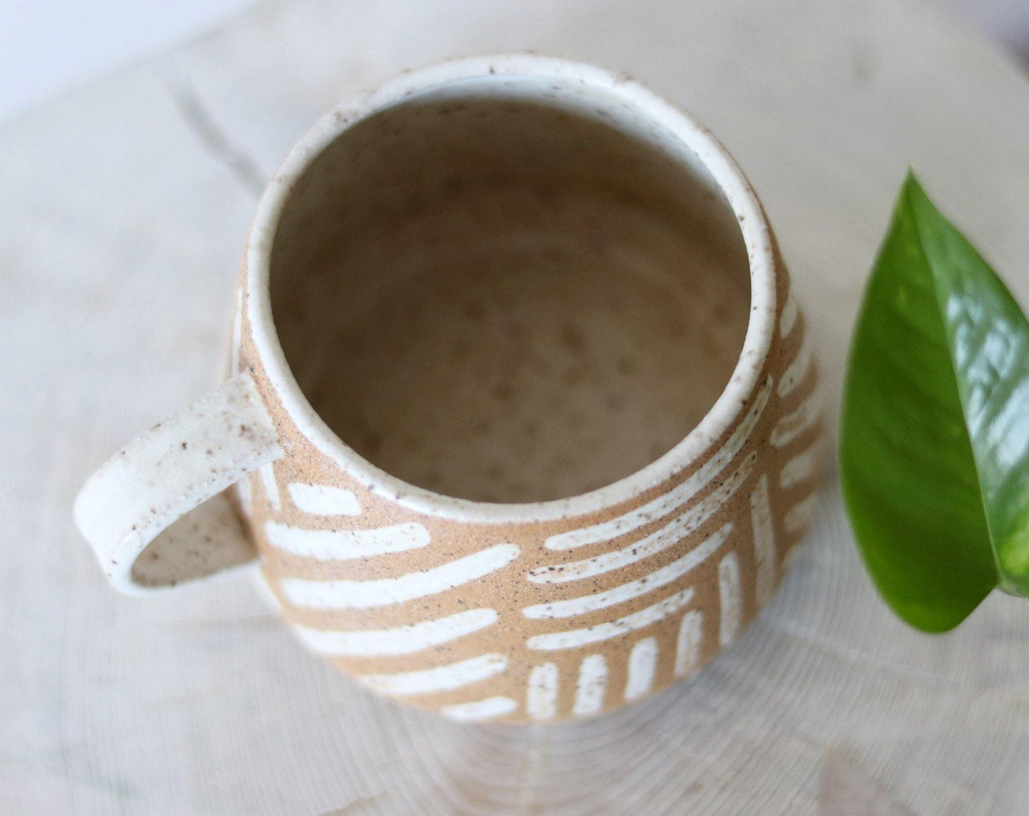 Handmade neutral mug with a speckled clay body and handpainted lines. Made by void and form ceramics.