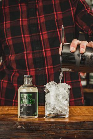 Bartender mixing Coin-style Margarita Cocktail syrup mix in glass bottle