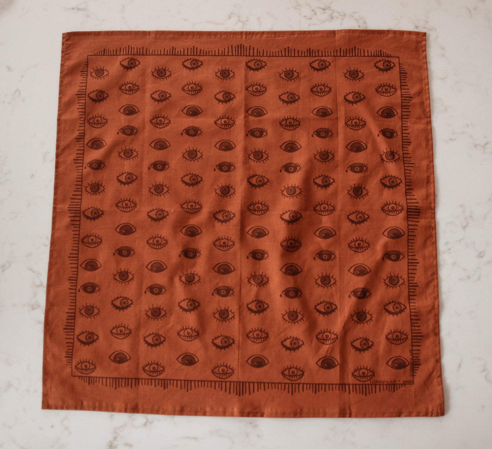 Rust colored bandana with brown eyeball print